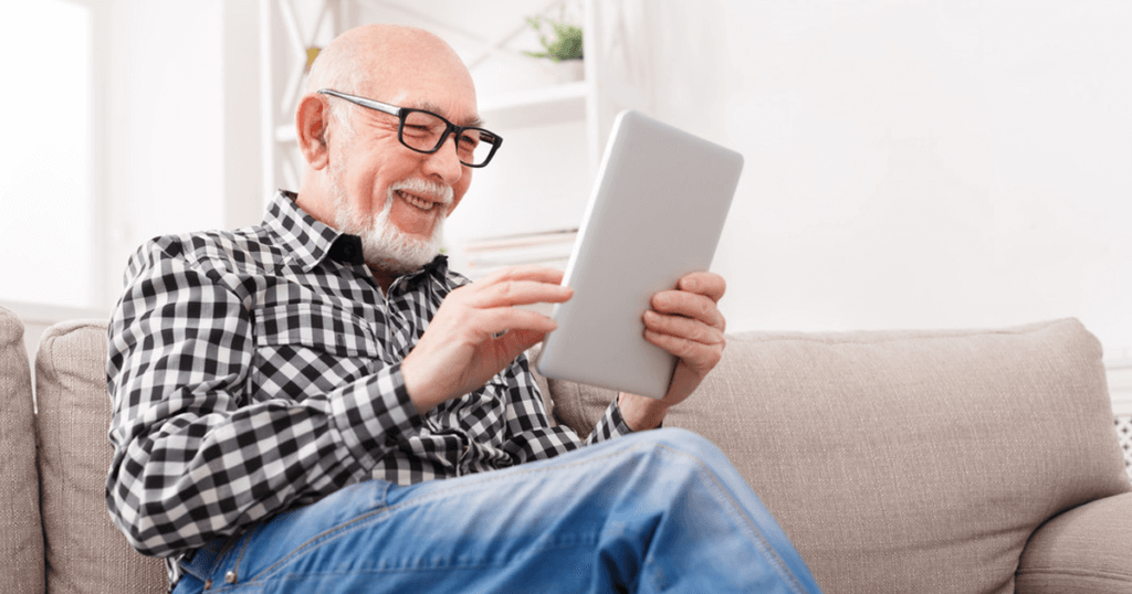 Elderly man smiling looking at tablet