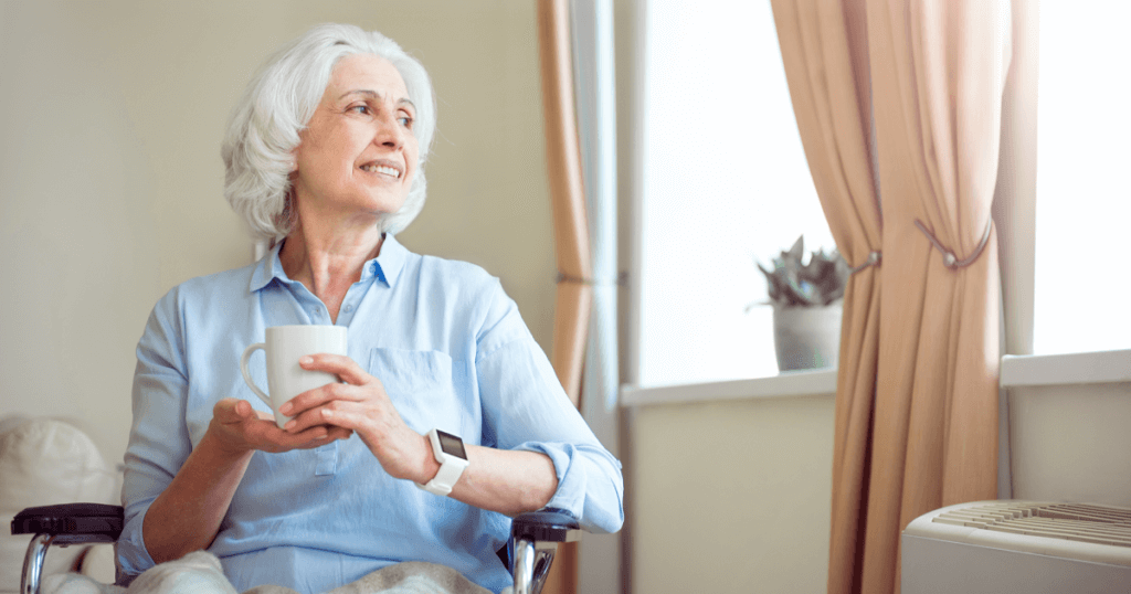 Elderly woman looking out the window holding a cup