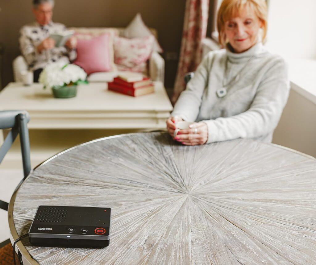 Woman having a cup of tea with her pendant and emergency alarm